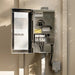 An open Kichler electrical panel box mounted on a beige exterior wall, showing the interior switchgear, terminal connections, and a small attached junction box below.