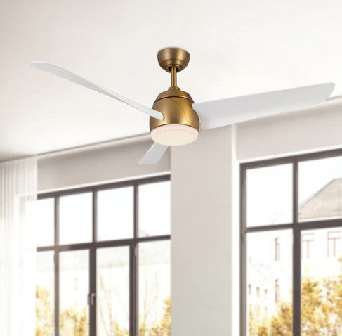Ceiling fan with gold finish and white blades in a room with large windows.