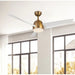 Ceiling fan with gold finish and white blades in a room with large windows.