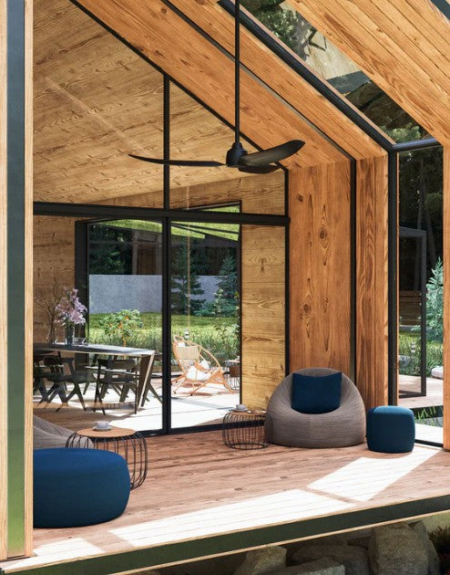 Modern indoor-outdoor living space with wooden walls, glass doors, and outdoor ceiling fan.
