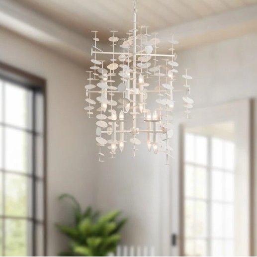 Modern chandelier hanging in a room with large windows and a plant.