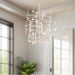 Modern chandelier hanging in a room with large windows and a plant.