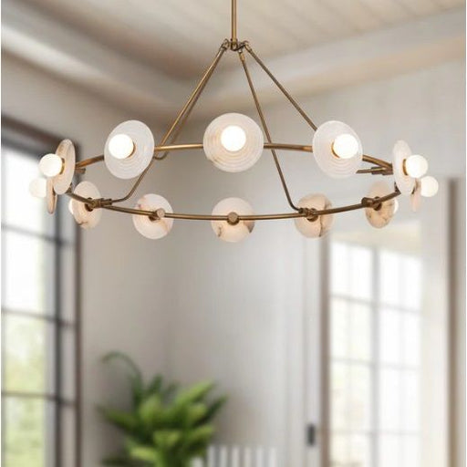 Modern chandelier with gold frame and white glass shades in a room with large windows.