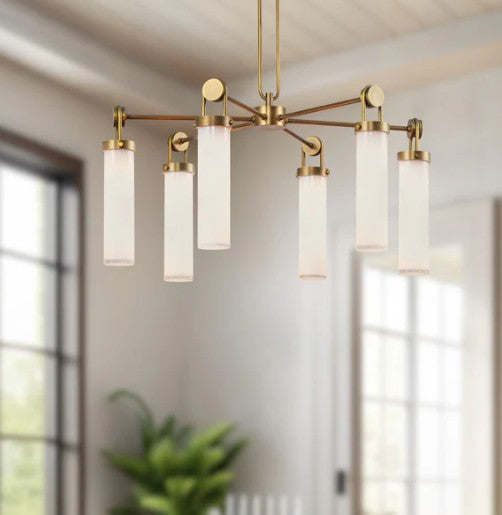 Modern chandelier with gold fixtures and white glass shades in a room with large windows.