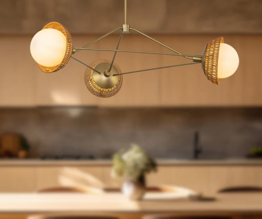 3 Matte Opal Glass globes on brushed gold metal arms with Rattan shades hanging  over island in a kitchen