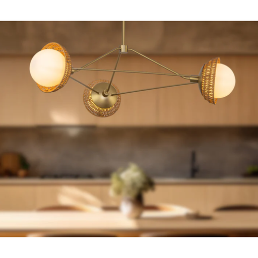 3 Matte Opal Glass globes on brushed gold metal arms with Rattan shades hanging  over island in a kitchen