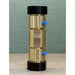 A brass cylindrical component with black end caps and small blue side valves, standing upright on a light surface against a textured green backdrop.