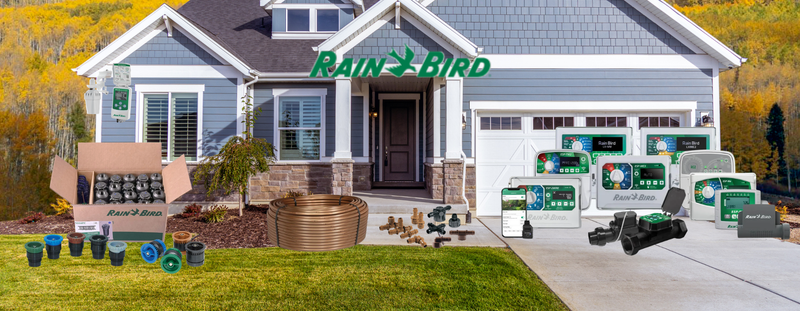 Rain Bird product display in front of a house with various irrigation equipment.